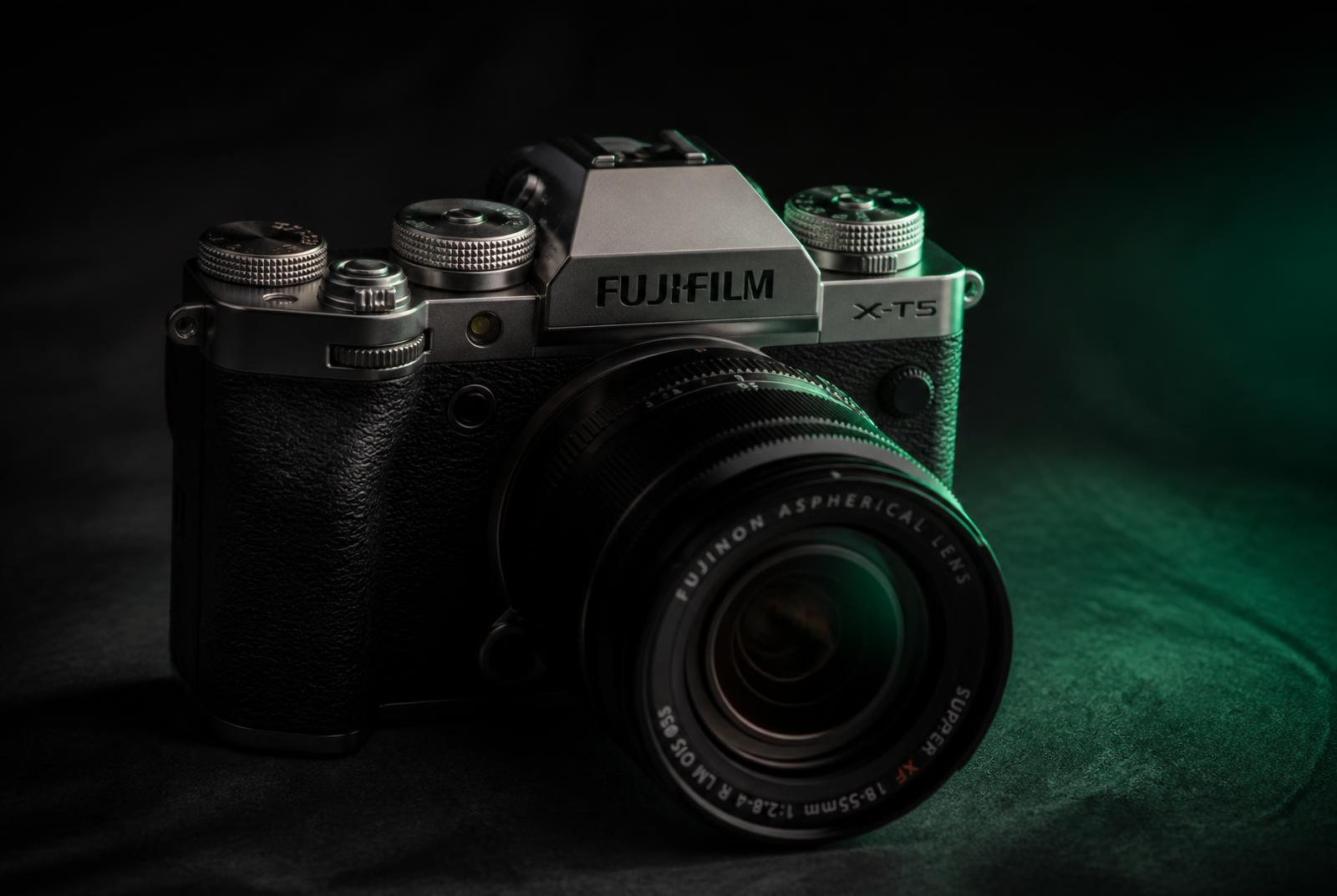 FUJIFILM mirrorless camera lit in green against a dark studio background